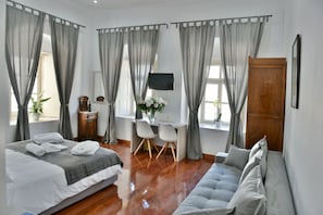 A bedroom with a bed, a sofa, a desk, and a TV.