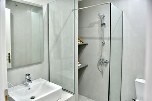 A modern bathroom with a glass-enclosed shower, a white sink, and a mirror.