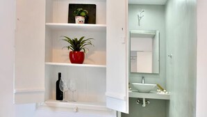 A modern bathroom with a glass shower enclosure, a white sink, and a mirror above the sink. - Douskos Port House (Hydra)