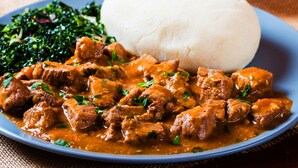 A plate of curry with meat, a portion of white rice, and a side of greens. - Masai Village Stay Tanzania (Monduli)