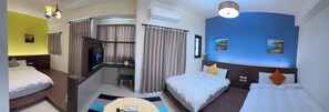 A hotel room with two beds, a TV, a desk, and an air conditioning unit.