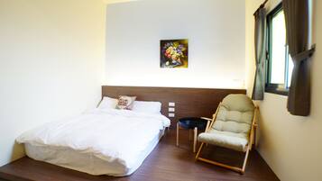 Een slaapkamer met een bed, een stoel, een schilderij aan de muur en een raam.