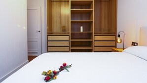 A bedroom with a large wooden wardrobe, a bed with white bedding, and a bedside lamp. - PARAISOL 3 Family Complex (Salou)