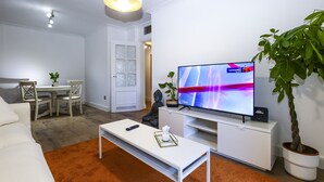 A modern living room with a flat-screen TV, white furniture, and a potted plant. - PARAISOL 3 Family Complex (Salou)