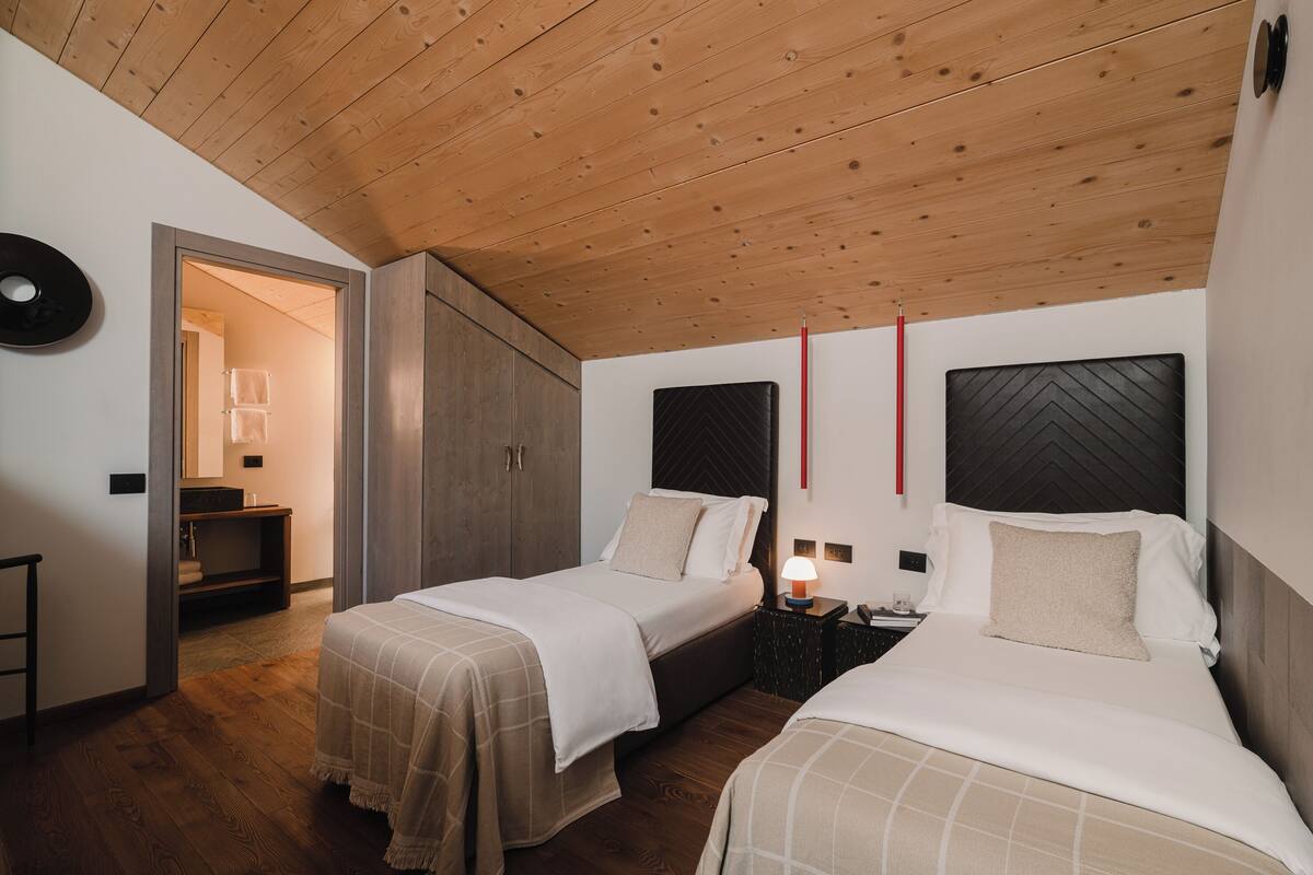 Un dormitorio con dos camas, techo de madera y un armario.