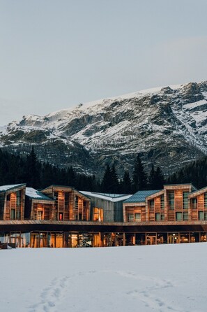 A modern lodge with multiple wooden cabins, set against a snowy mountain backdrop. - Aethos Monterosa (Ayas)
