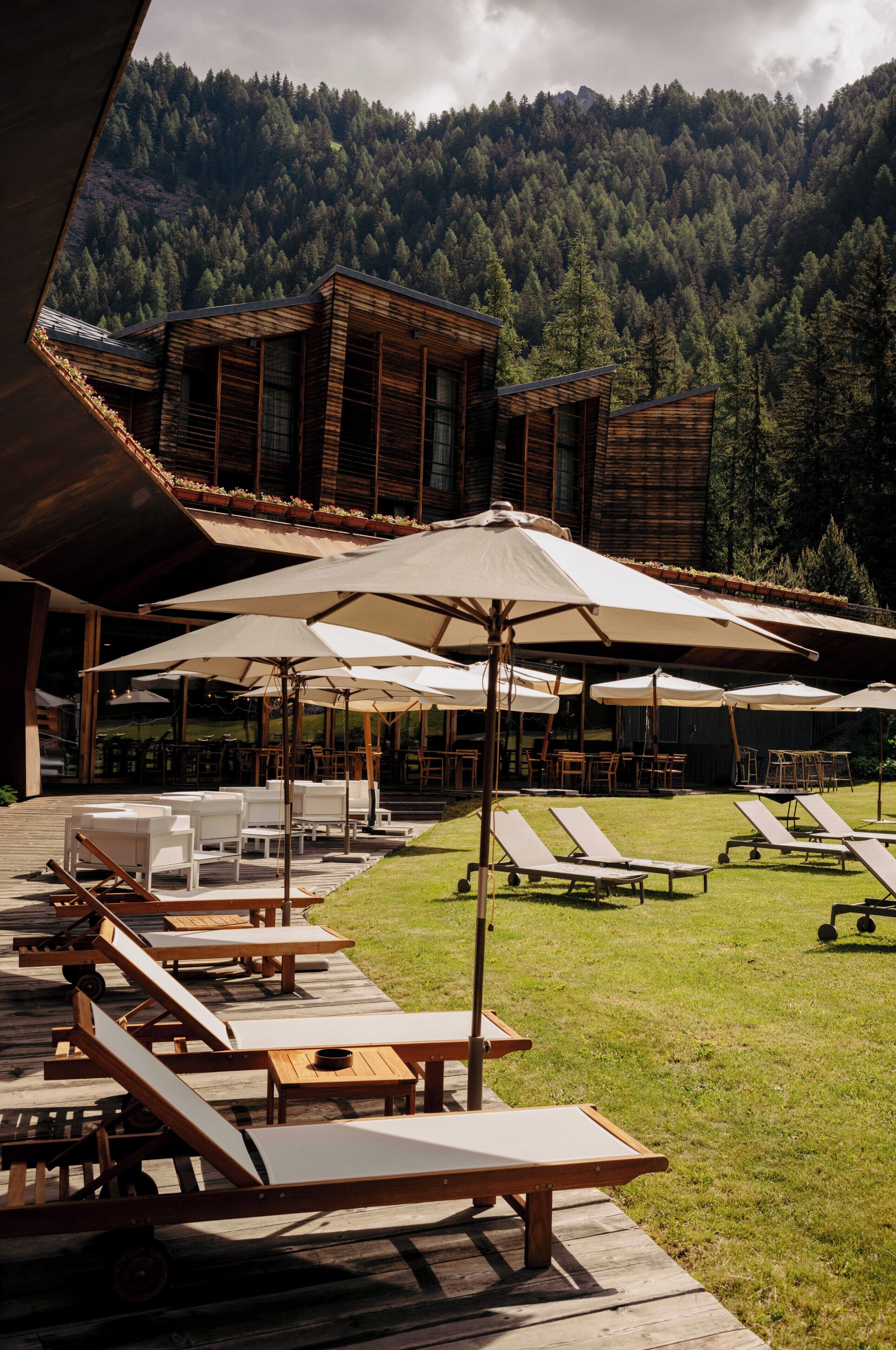 A resort with outdoor seating, umbrellas, and a view of a forested mountain.