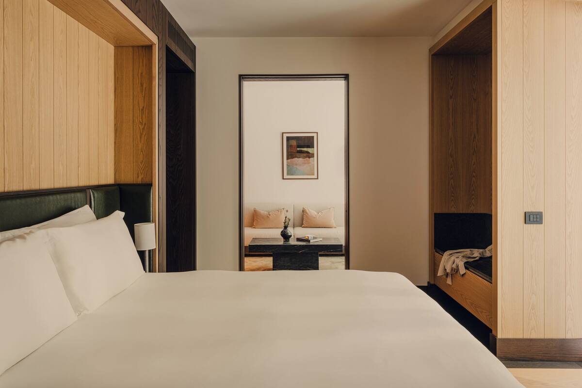 Una habitación de hotel con una cama grande, una mesita de noche, un sofá y un armario de madera.