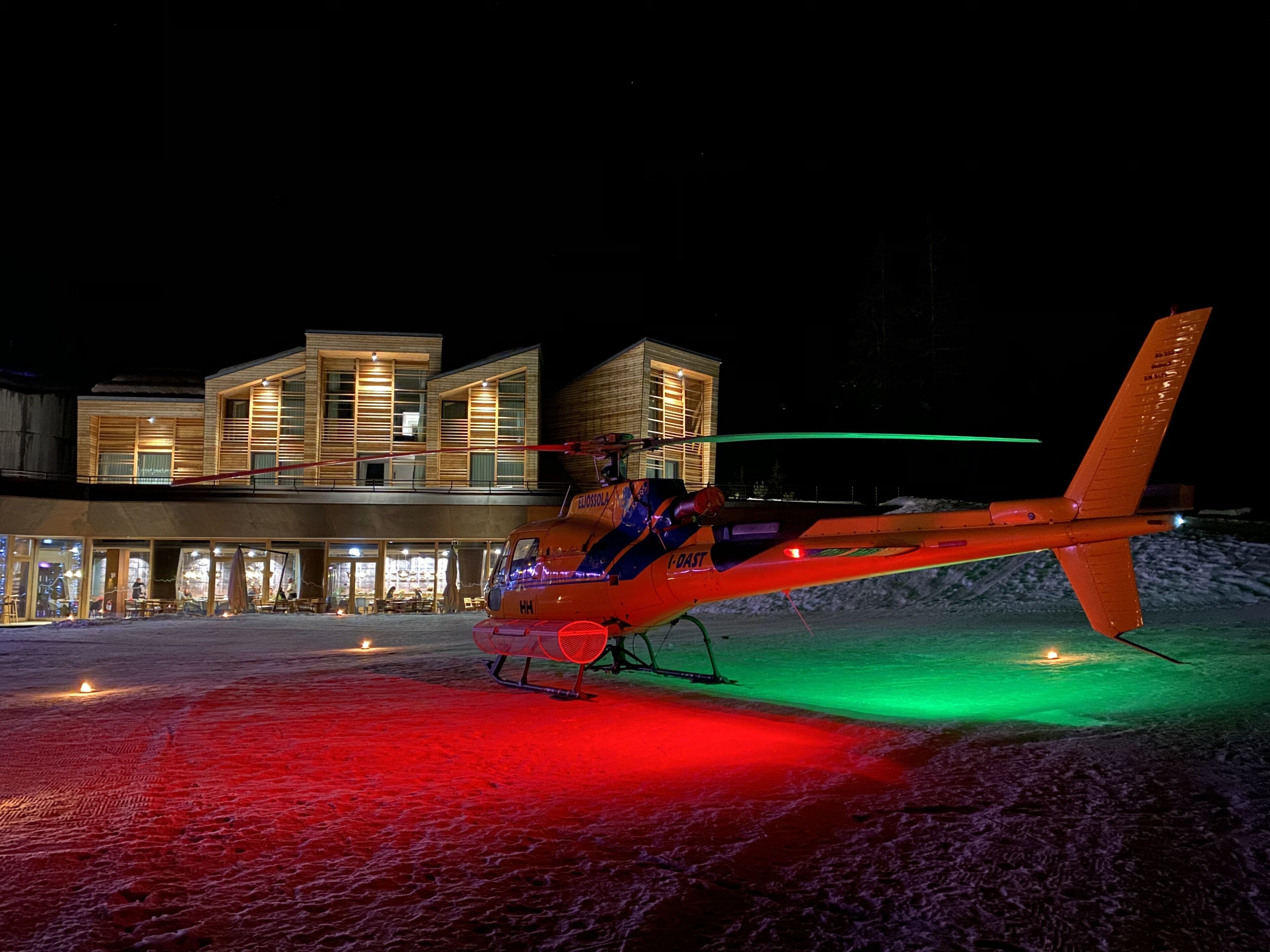 A helicopter parked in front of a modern building with a glass facade.