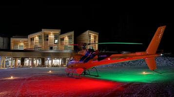 A helicopter parked in front of a modern building with a glass facade.