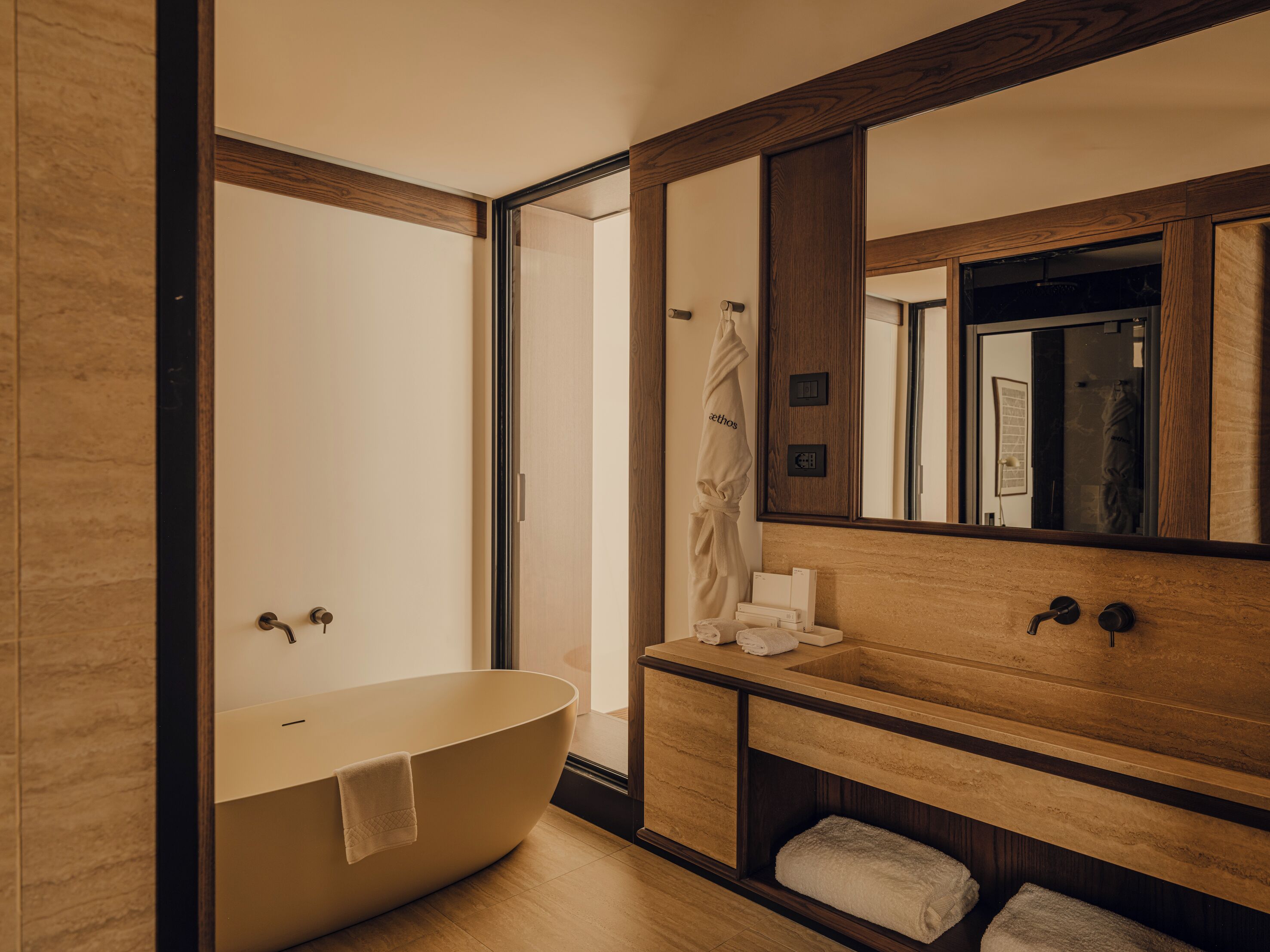 Een moderne badkamer met een vrijstaand bad, een houten wastafelmeubel en een grote spiegel.
