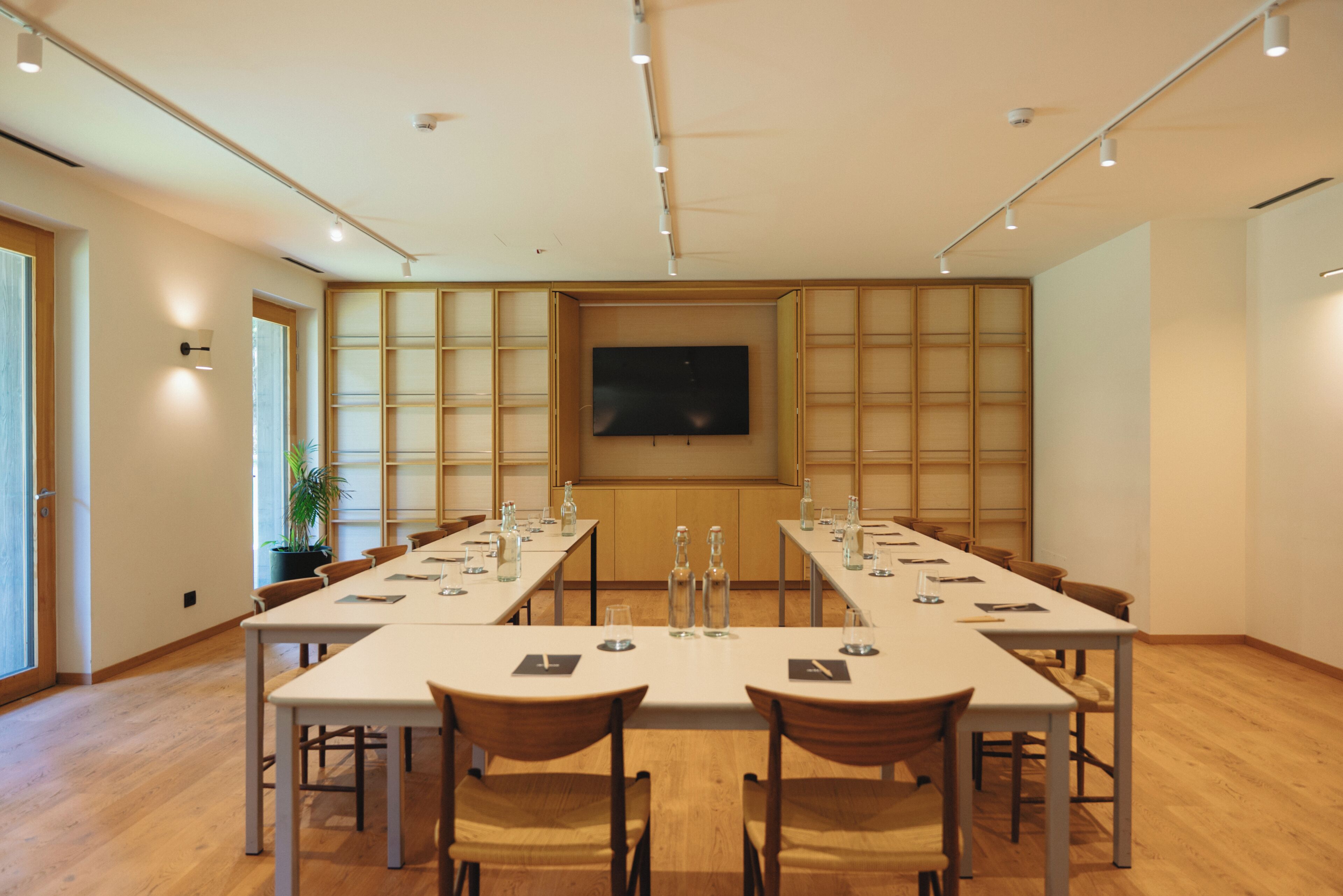 Une salle de conférence avec une longue table, des chaises et un écran de télévision fixé au mur.