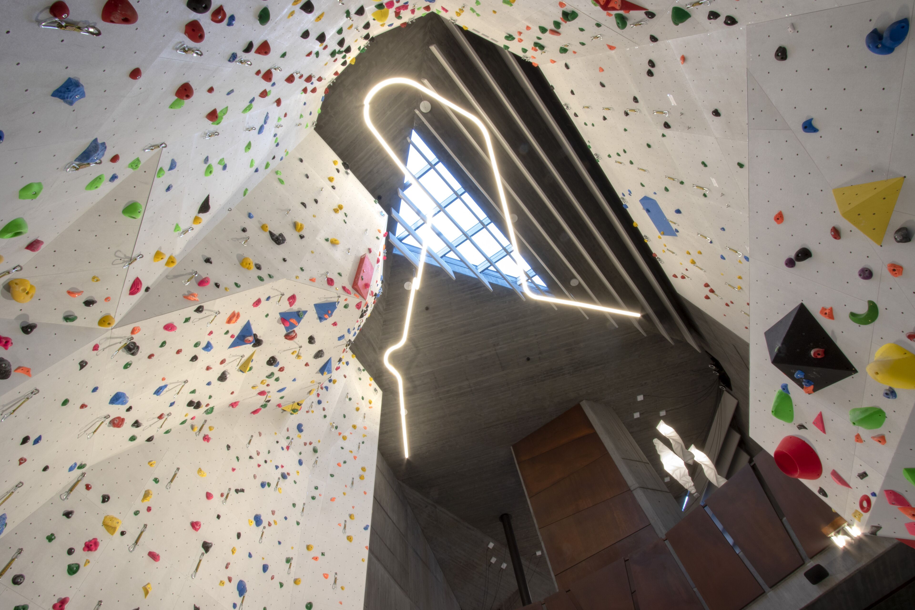 Een klimmuur met kleurrijke grepen en een geometrische lamp.