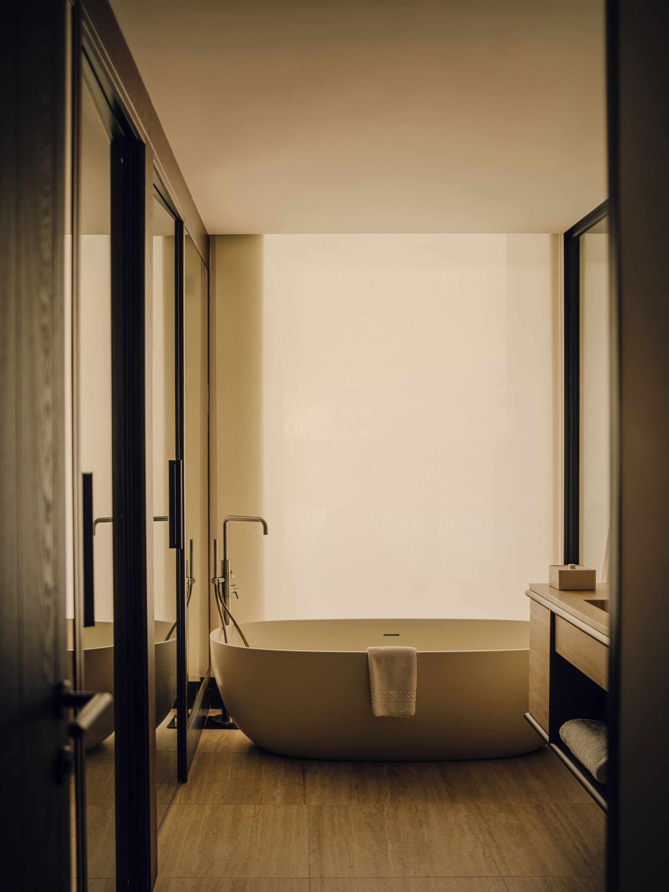 A modern bathroom with a freestanding bathtub, a glass shower enclosure, and a wooden vanity.