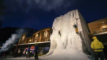 Una gran estructura de hielo con gente escalando y esquiando, rodeada de edificios.