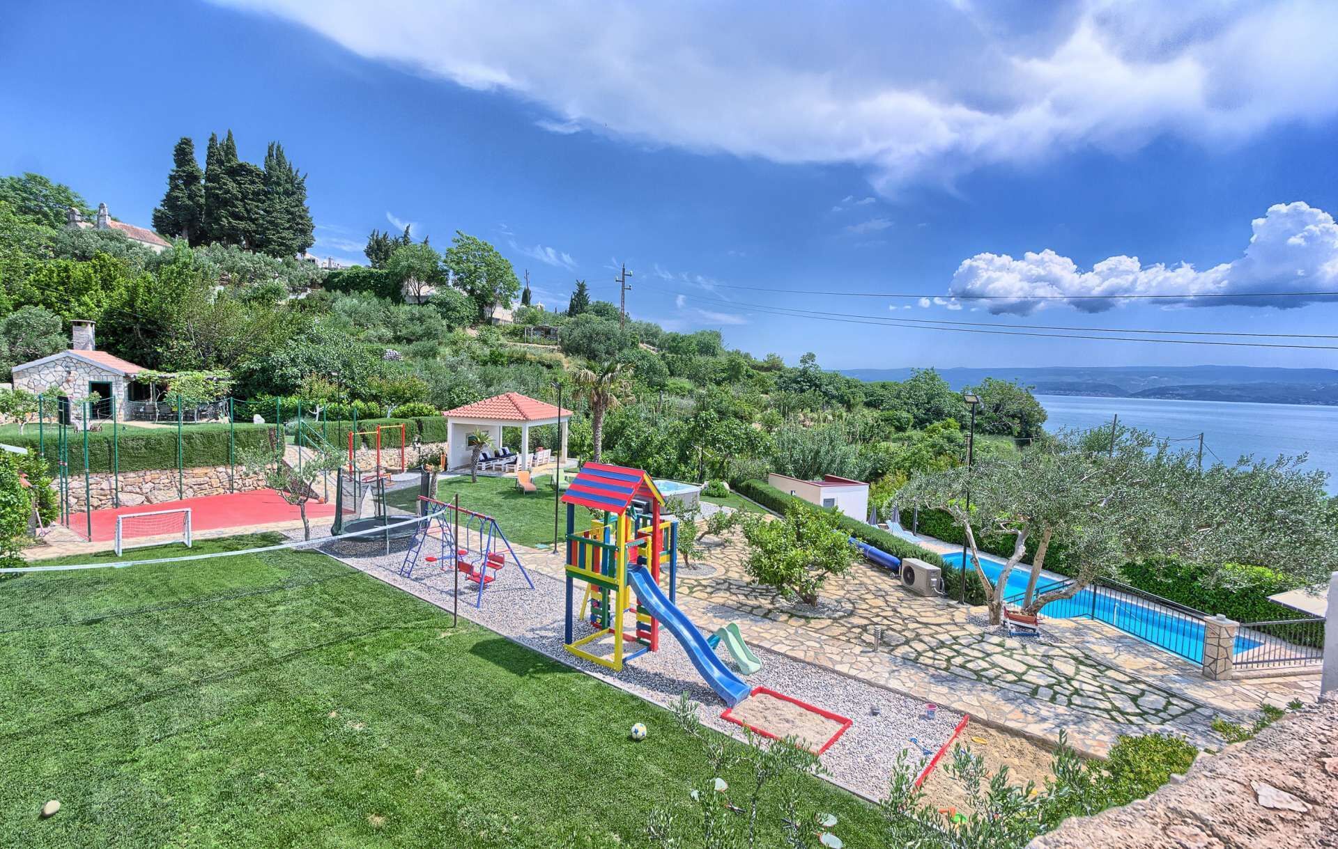 A playground with slides and swings, a small pool, and a stone patio area.
