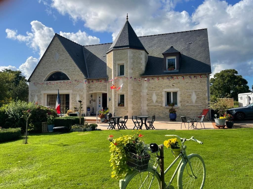 A stone building with a central tower and two wings, outdoor seating, and a bicycle in the foreground.