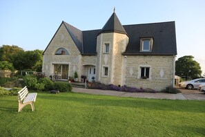 A stone house with a steeply pitched roof, a central tower, and a front porch with potted plants. - Chambre d'hôtes Mon Taj Mahal (Gueron)