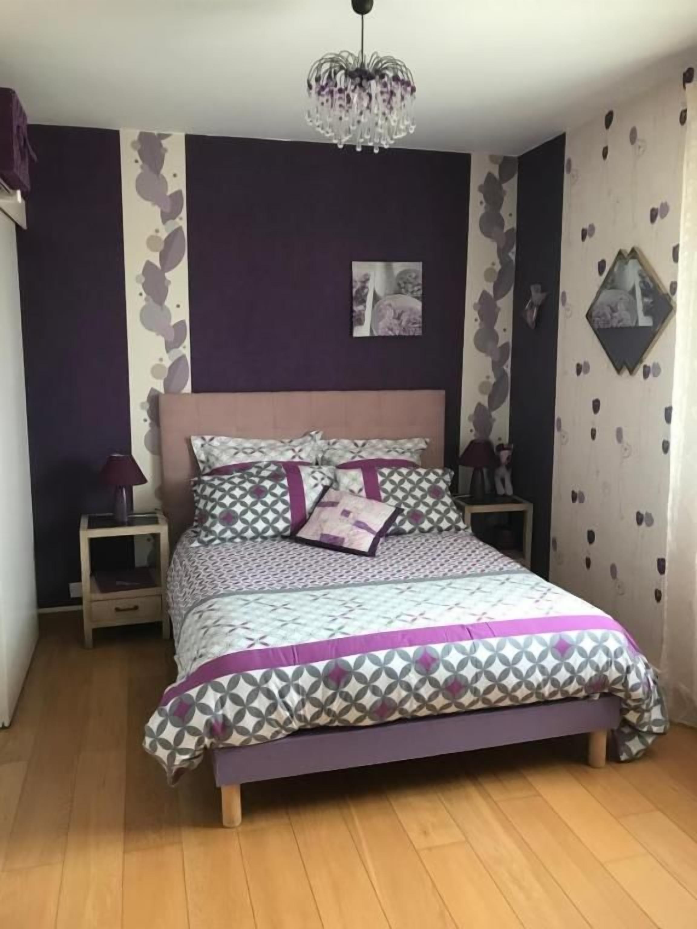 Ein Schlafzimmer mit einem Bett, einem Nachttisch, einer Lampe, einer Chandelier und einer Wand mit einem dekorativen Muster.