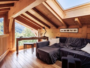 A cozy cabin with a wooden interior, a sofa, a table, and a view of the outdoors.
