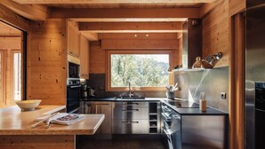 Una cocina moderna con paredes de madera, electrodomésticos de acero inoxidable y un ventanal con vistas al exterior.