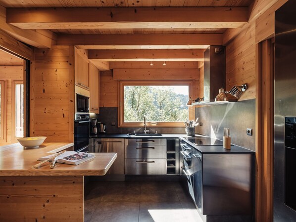 A modern kitchen with wooden walls, stainless steel appliances, and a window providing a view of the outdoors.