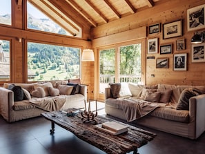 Una habitación acogedora con dos sofás, una mesa de centro rústica y cuadros enmarcados en la pared.