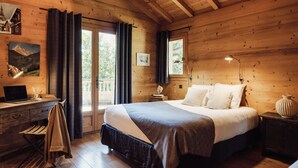 Un dormitorio de cabaña de madera con cama, escritorio y ventana con cortinas.