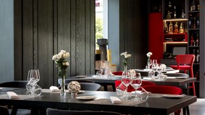 A modern dining area with tables set for two, featuring clear glassware and white flowers. - Il San Cristoforo (Ercolano)
