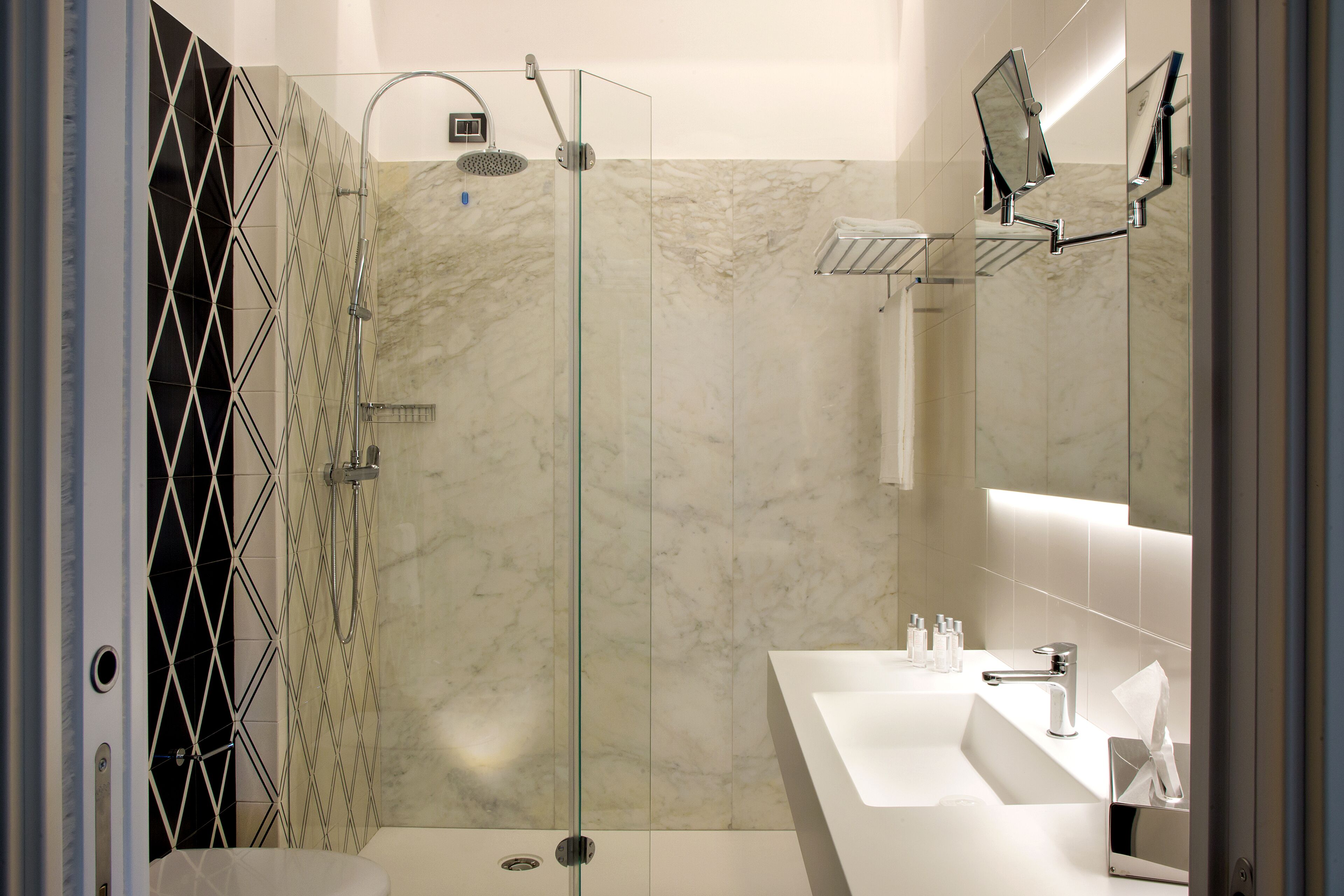 A modern bathroom with a glass-enclosed shower, a white sink, and a large mirror.