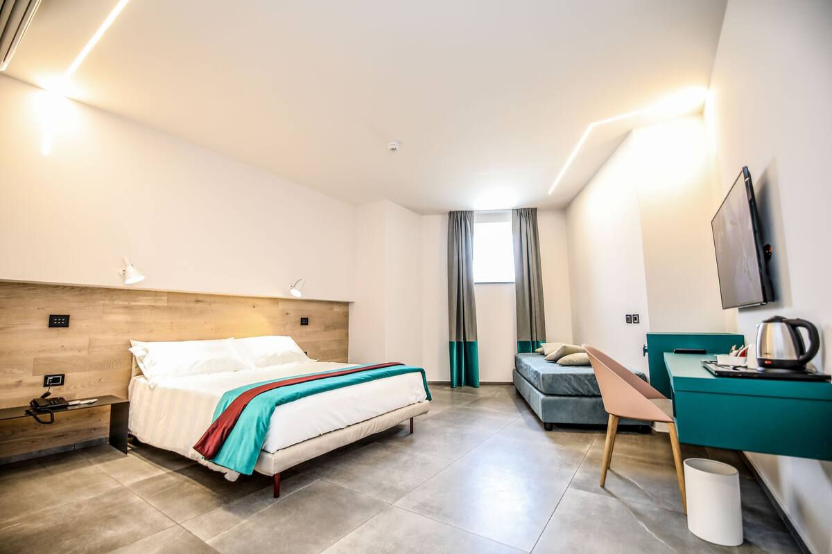 A modern hotel room with a bed, desk, and television.