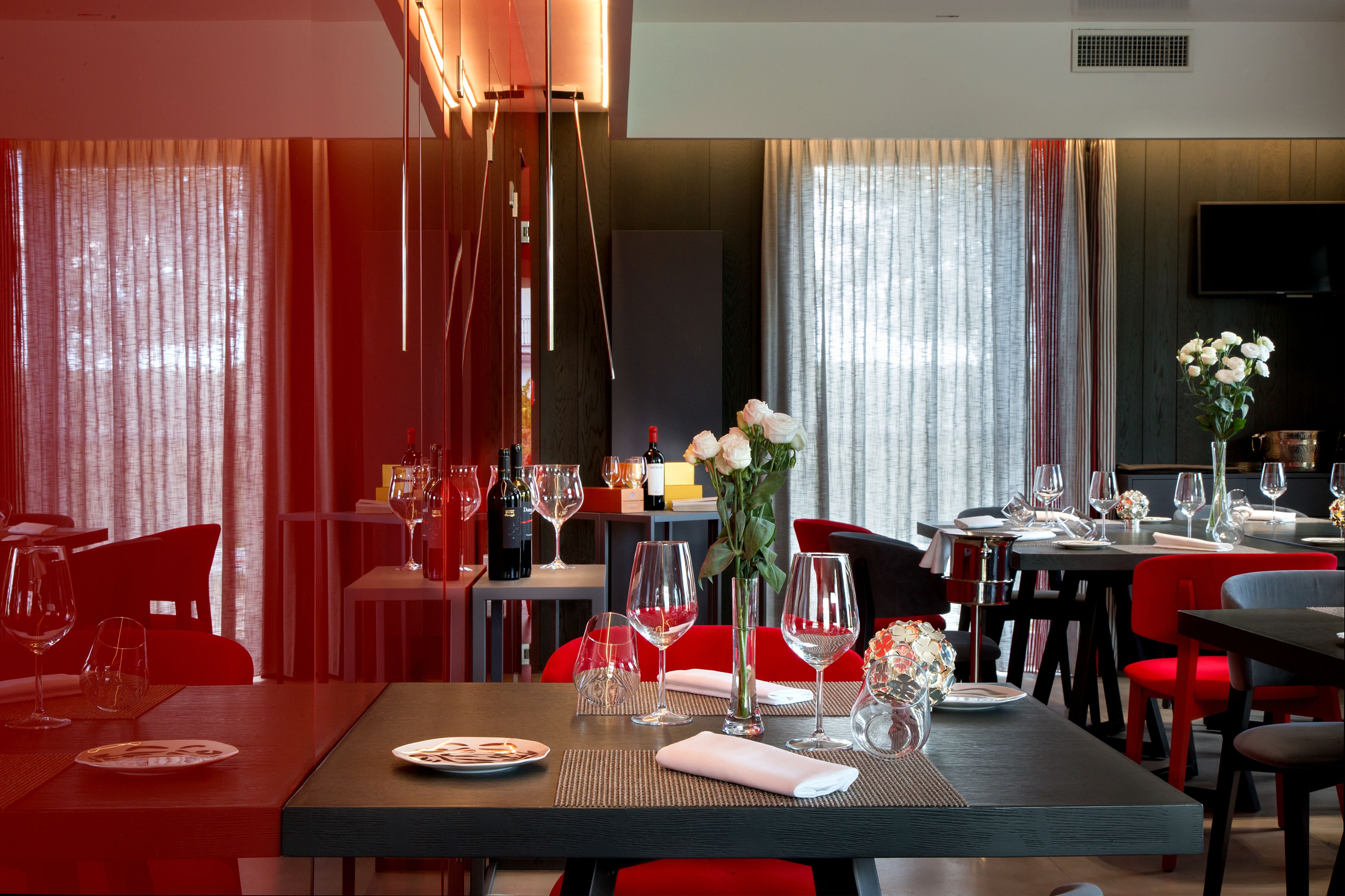 A dining area with tables set for a meal, including wine glasses and plates.