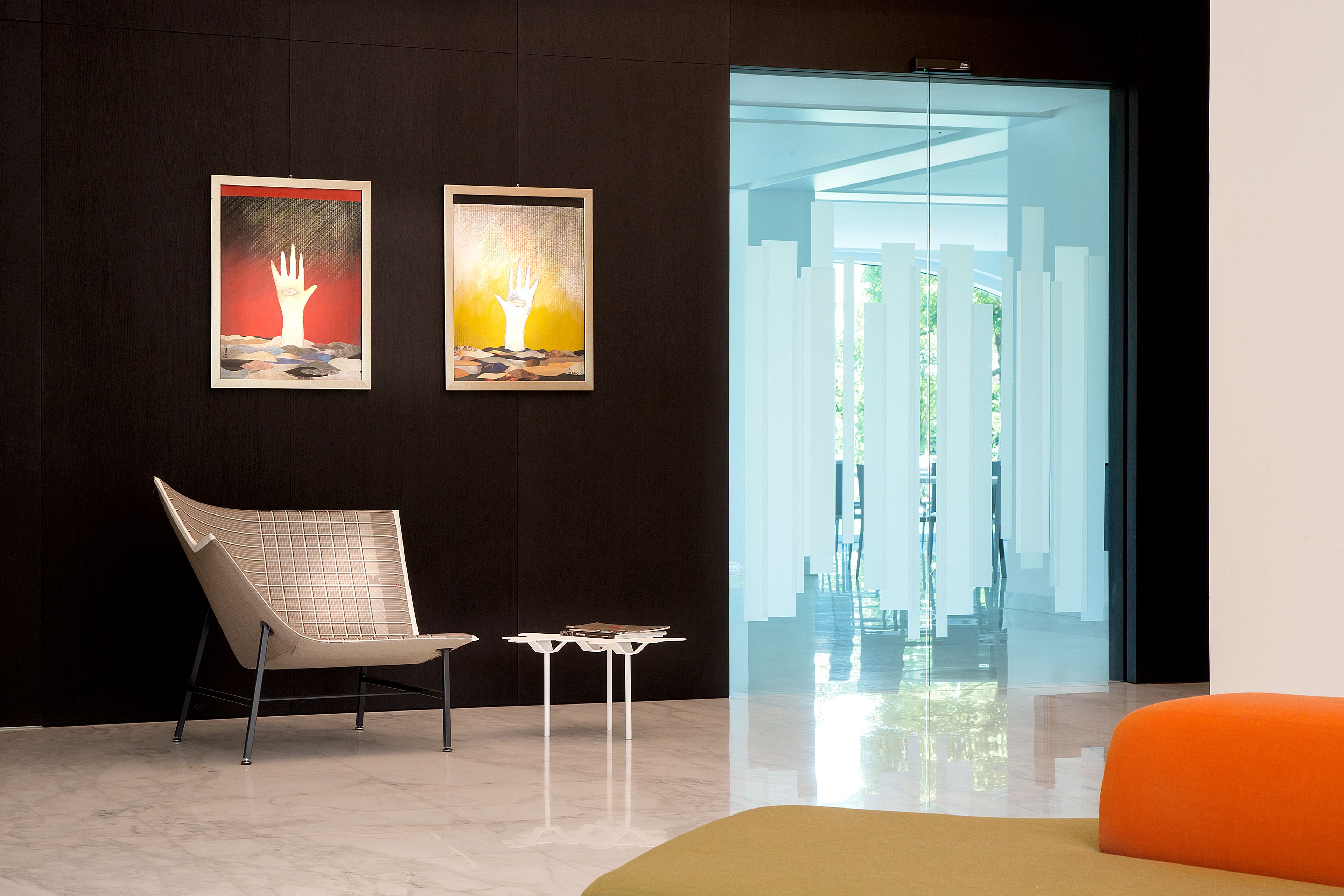 A modern interior with a chair, a small table, and two framed artworks on the wall.