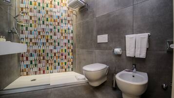 A modern bathroom with a shower, toilet, and bidet.