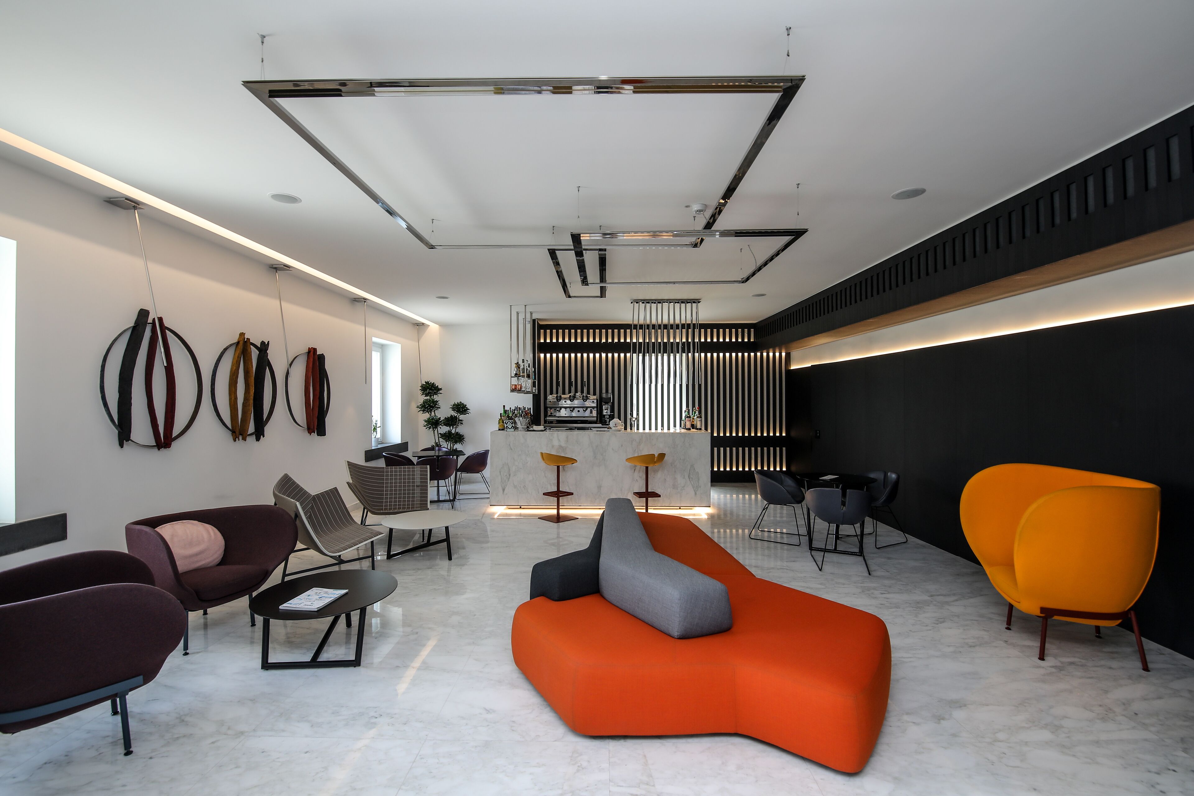Un vestíbulo moderno con mostrador de recepción, zona de estar y un amplio sofá naranja.