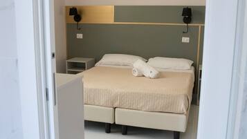 Een moderne hotelkamer met een groot bed, twee nachtkastjes en een hoofdeinde met wandlampen.