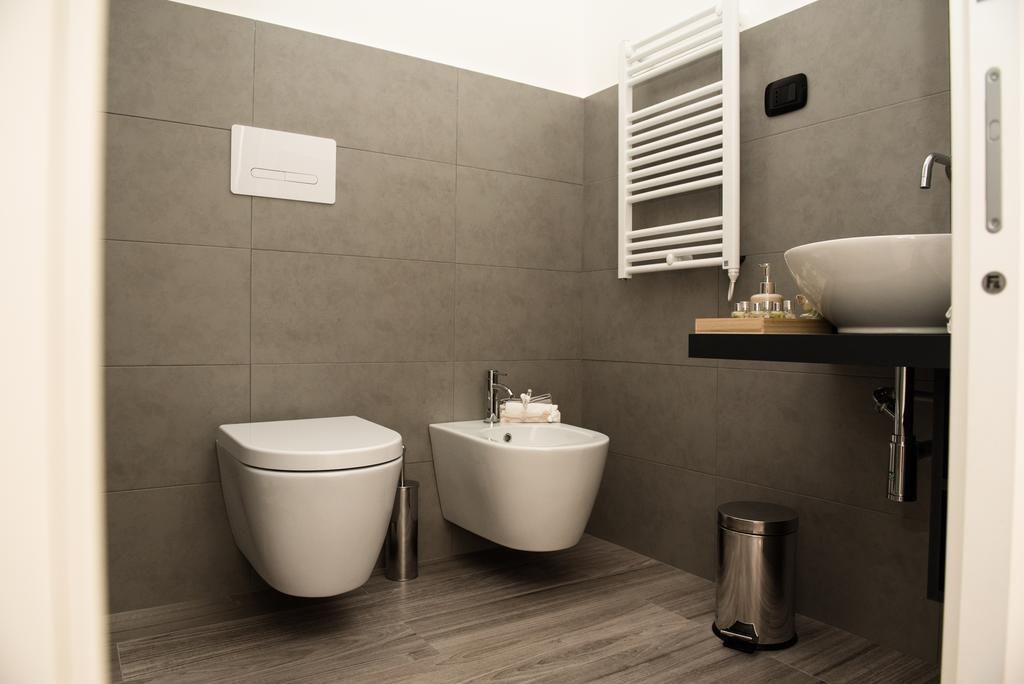 A modern bathroom with a toilet, bidet, sink, and towel rack.
