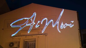 A building with a neon sign spelling "Shinomi" in cursive. - Milazzo INN AiMori (Milazzo)