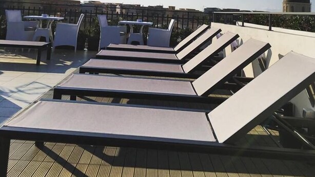 A rooftop terrace with sun loungers and tables, offering a clear view of the city skyline. - Milazzo INN AiMori (Milazzo)