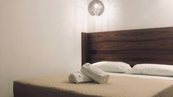 Una cama bien hecha con cabecera de madera, una lámpara colgante y un suelo con textura.