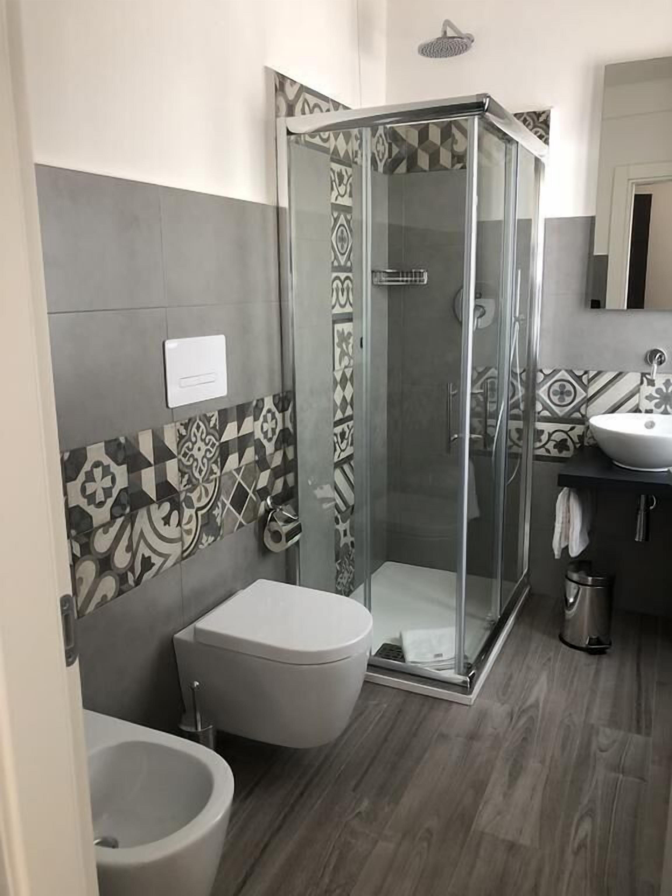 A modern bathroom with a shower, toilet, bidet, and sink.