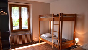 Camera con letto a castello, finestra, termosifone e lampada da comodino.