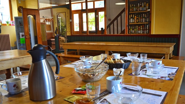 Un tavolo da pranzo con una caffettiera, ciotole, bicchieri e un menu.