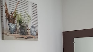 Un bagno con un lavandino bianco, uno specchio e una TV fissata al muro.