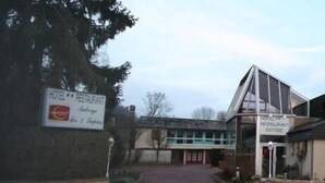 Un bâtiment avec une enseigne indiquant «HÔTEL-RESTAURANT» et «LES 2SAPINS».