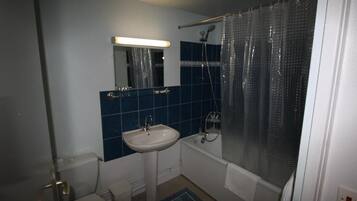 Une salle de bain équipée d’un lavabo, de toilettes, d’une baignoire et d’un rideau de douche.