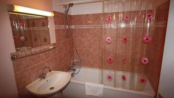 A bathroom with a bathtub, a sink, and a mirror.