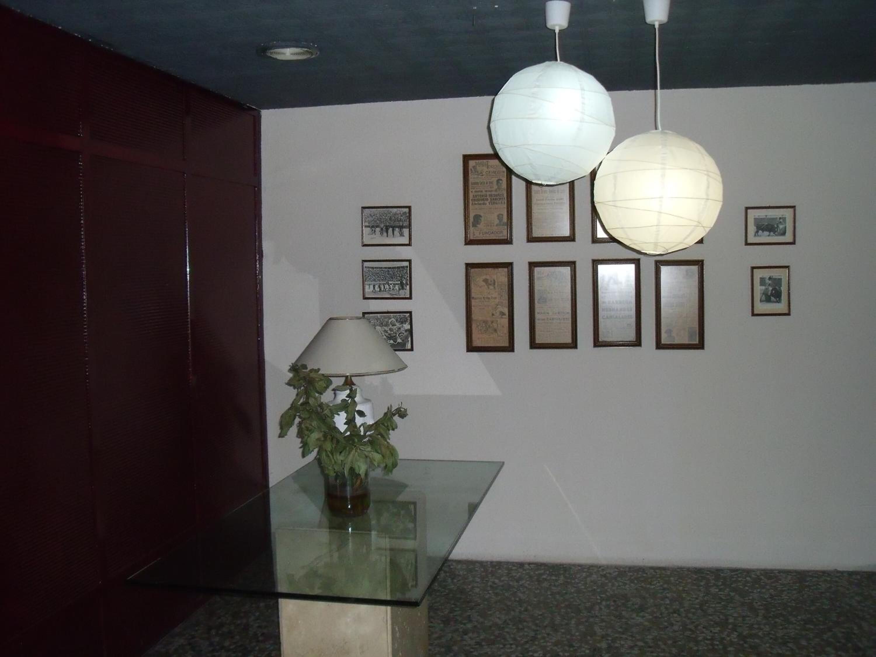 A lobby with a glass table, a potted plant, and framed certificates on the wall.