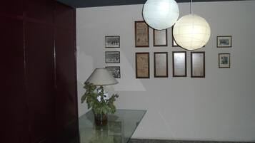 A lobby with a glass table, a potted plant, and framed certificates on the wall.