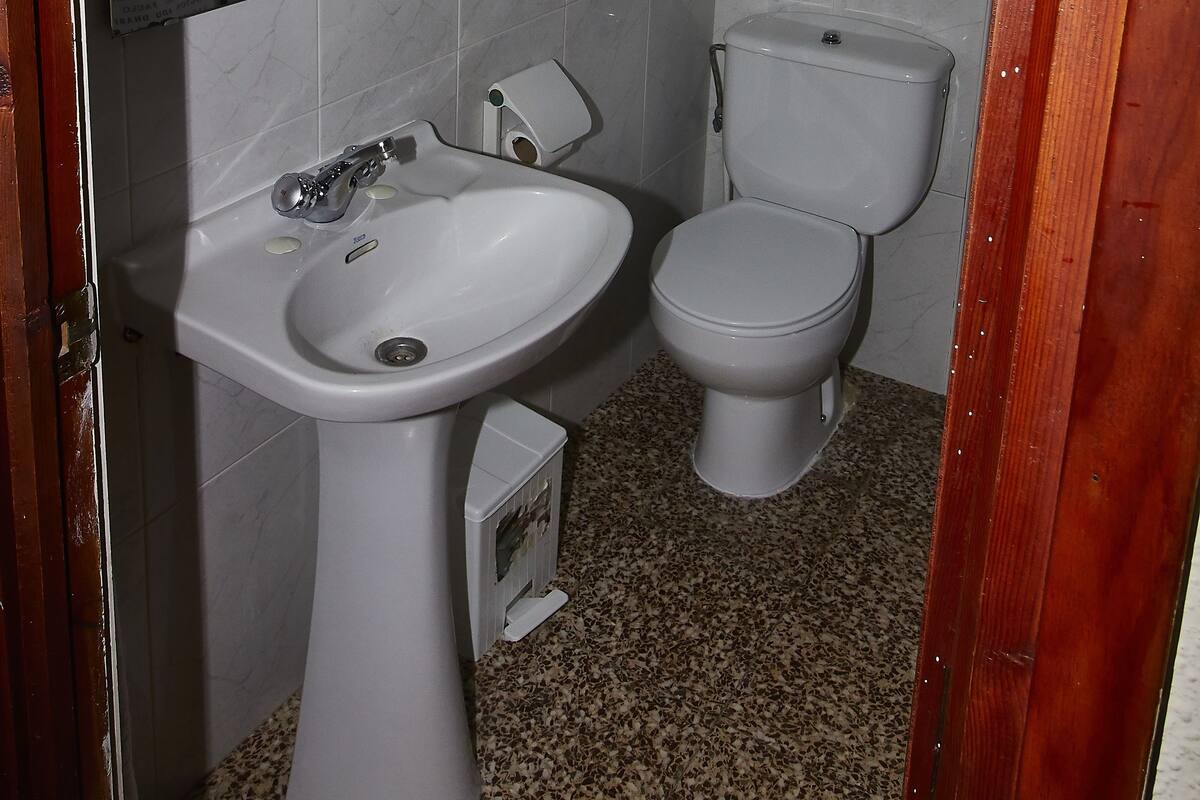 A small bathroom with a white sink, toilet, and mirror.